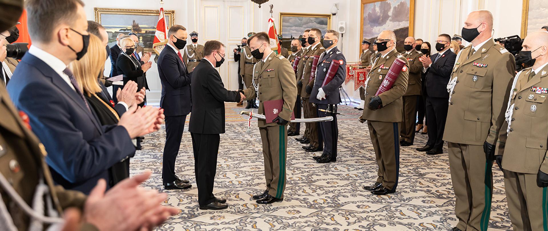 Na zdjęciu widać ministra Mariusza Kamińskiego składającego gratulacje jednemu z nominowanych generałów SG i innych uczestników uroczystości w Belwederze.