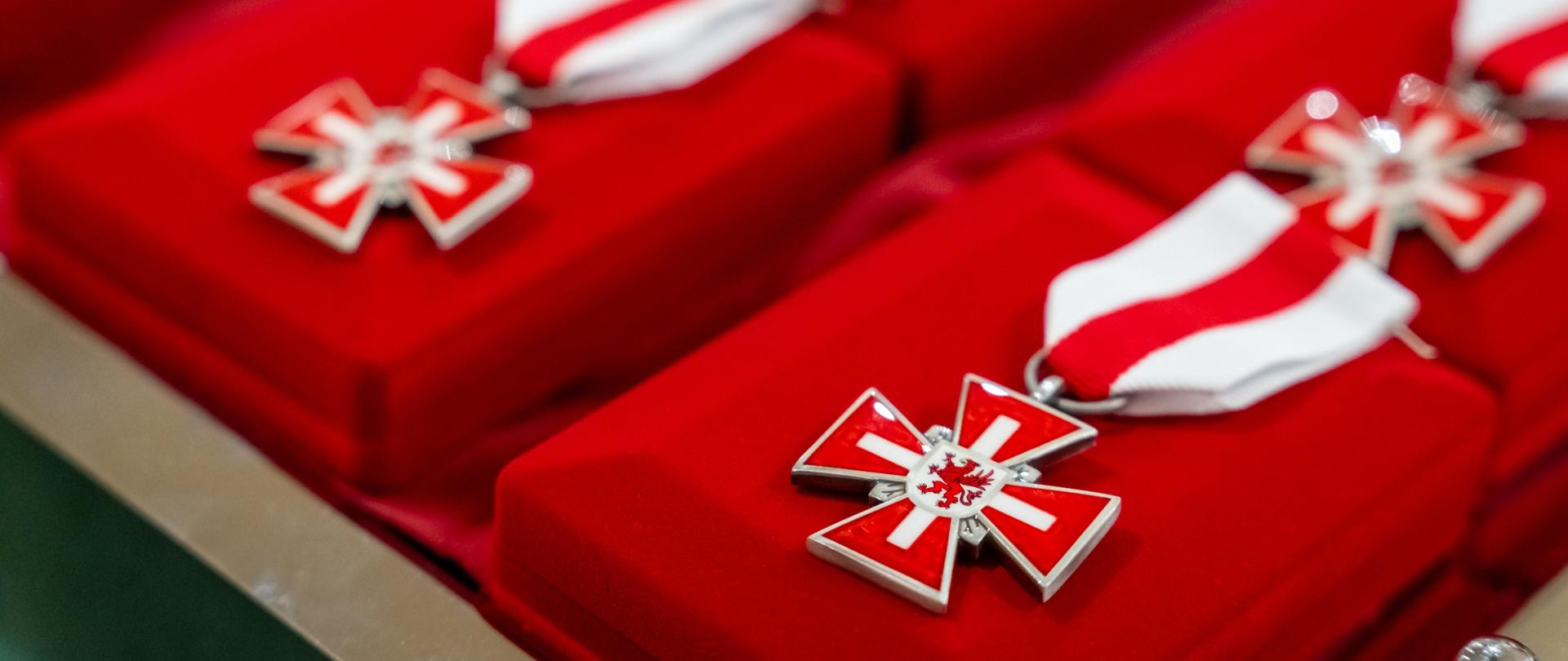 zdjęcie przedstawia zbliżenie na ordery na czerwonych aksamitnych pudełkach