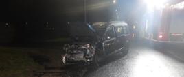 Wypadek w miejscowości Police Średnie gm. Kościelec. Zdjęcie przedstawia przód uszkodzonego samochodu w porze nocnej oraz stojący obok pojazd pożarniczy, który oświetla teren prowadzonych działań