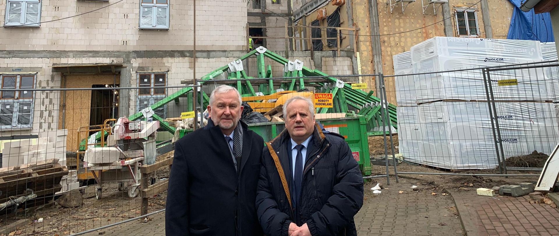 Dwóch mężczyzn rozmawia przed budynkiem Szpitala