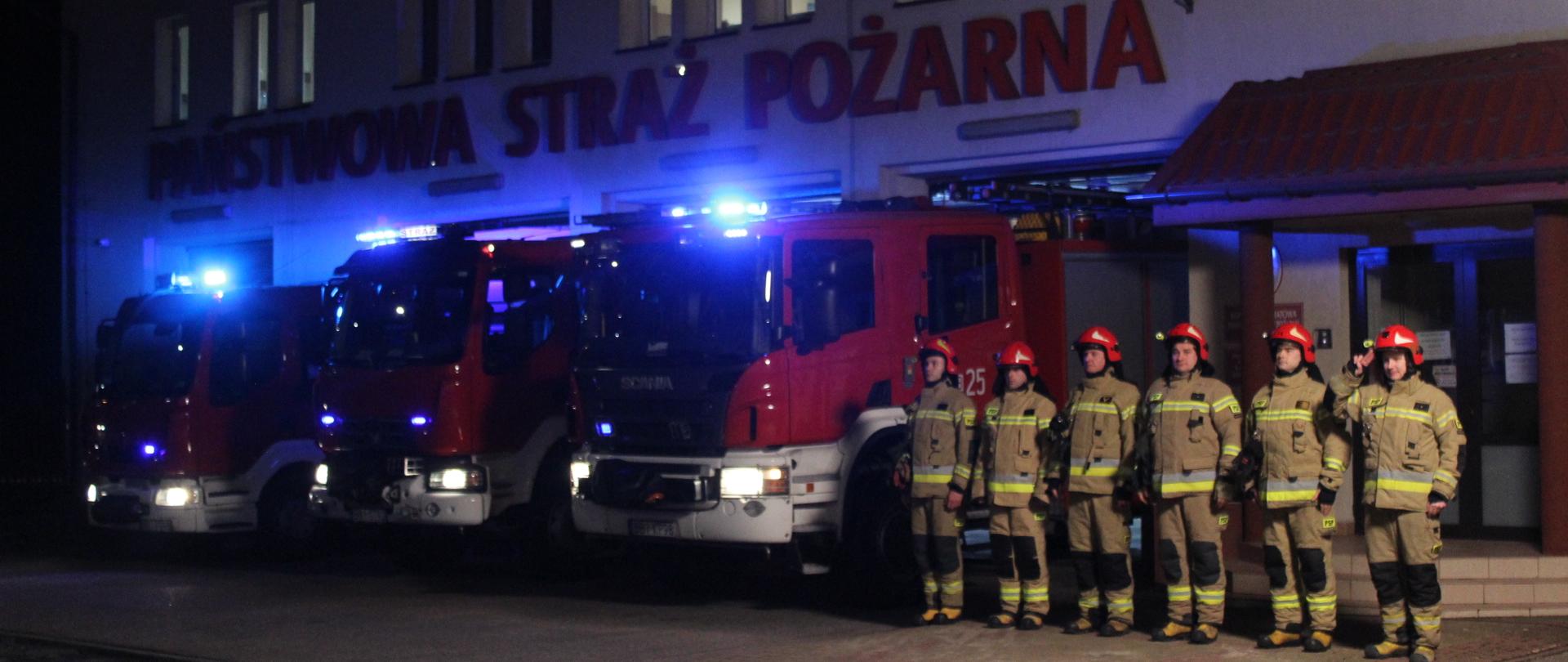 Strażacy oraz samochody ratowniczo-gaśnicze z włączonymi sygnałami świetlnymi przed Komendą Powiatową PSP w Bielsku Podlaskim podczas akcji "Minuta dla druhów z Czernikowa"