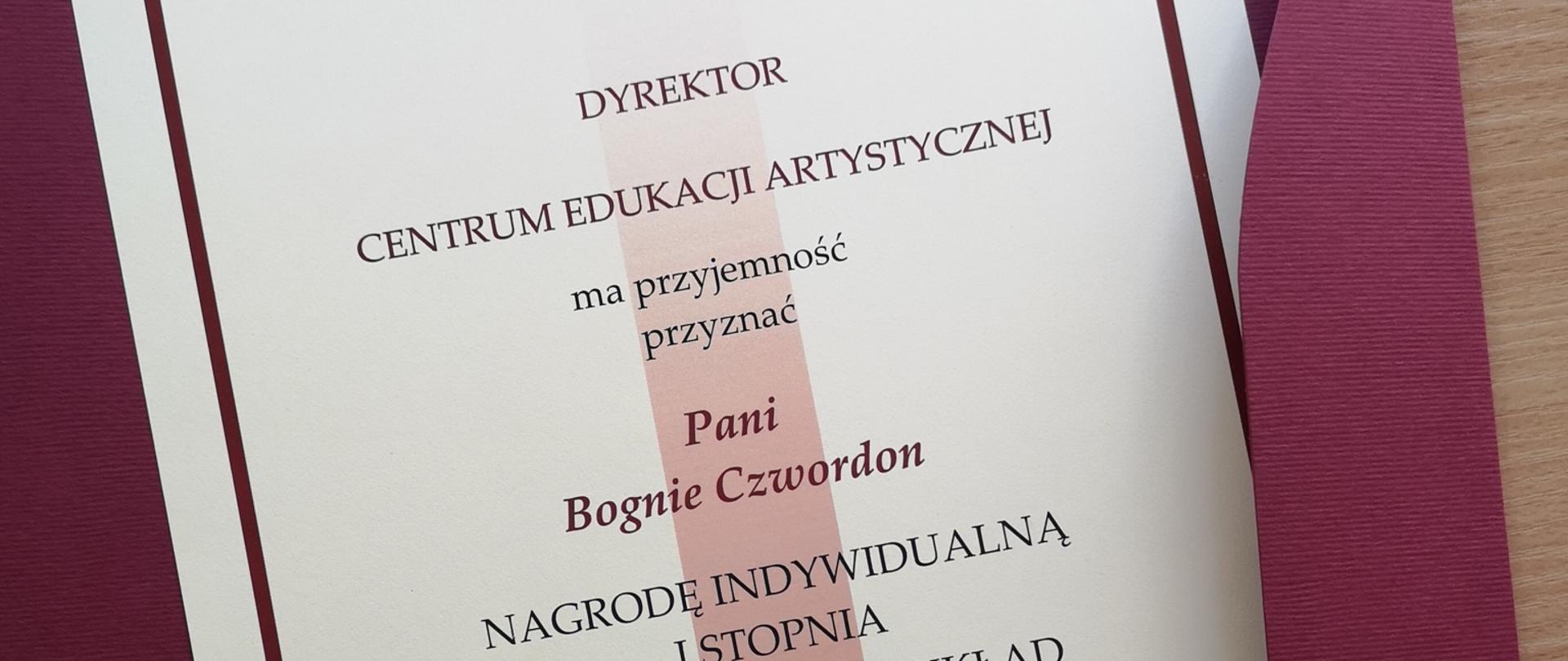 Zdjęcie dyplomu w bordowej teczce z napisemL: Dyrektor CEA ma przyjemność przyznać Pani Bognie Czwordon nagrodę indywidualną I stopnia za szczególny wkład w rozwój edukacji artystycznej w Polsce"