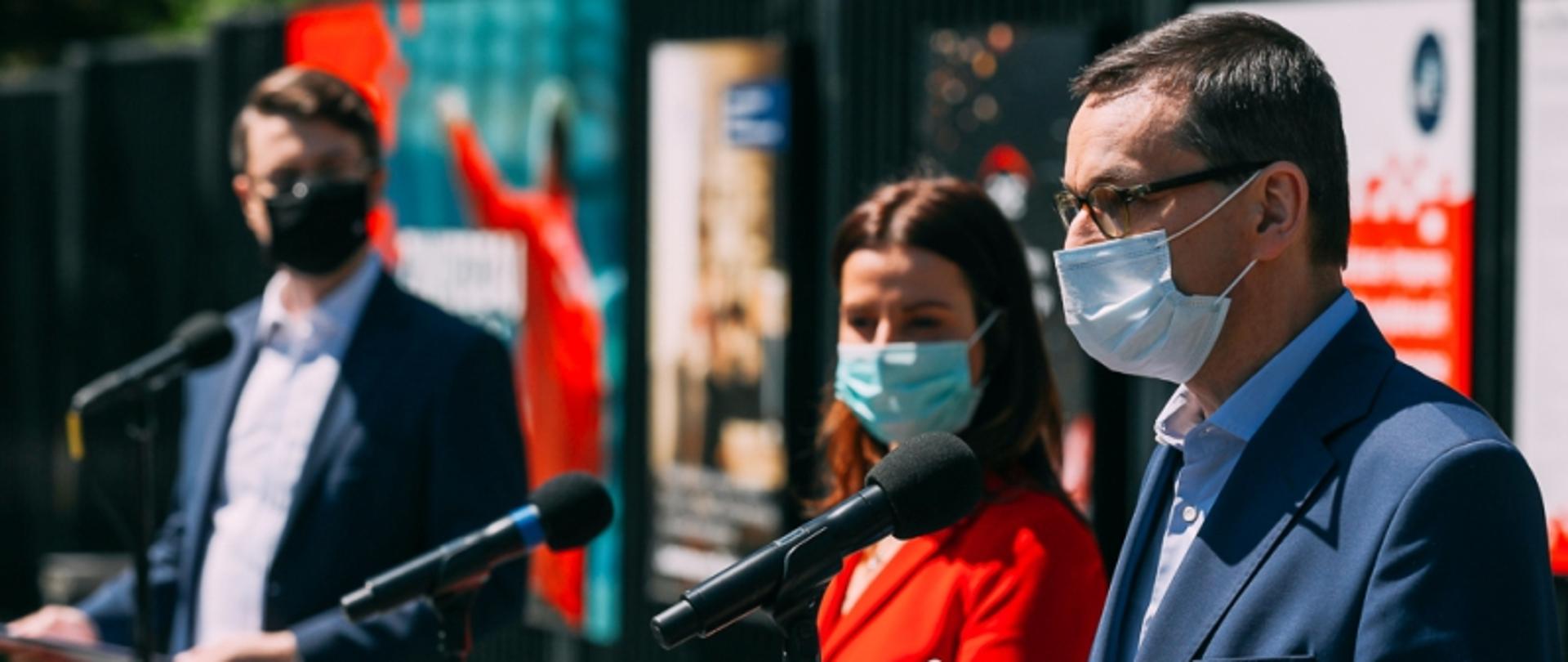 Na błoniach Stadionu Narodowego stoi Premier Mateusz Morawiecki, minister sportu Danuta Dmowska-Andrzejuk, rzecznik rządu Piotr Muller