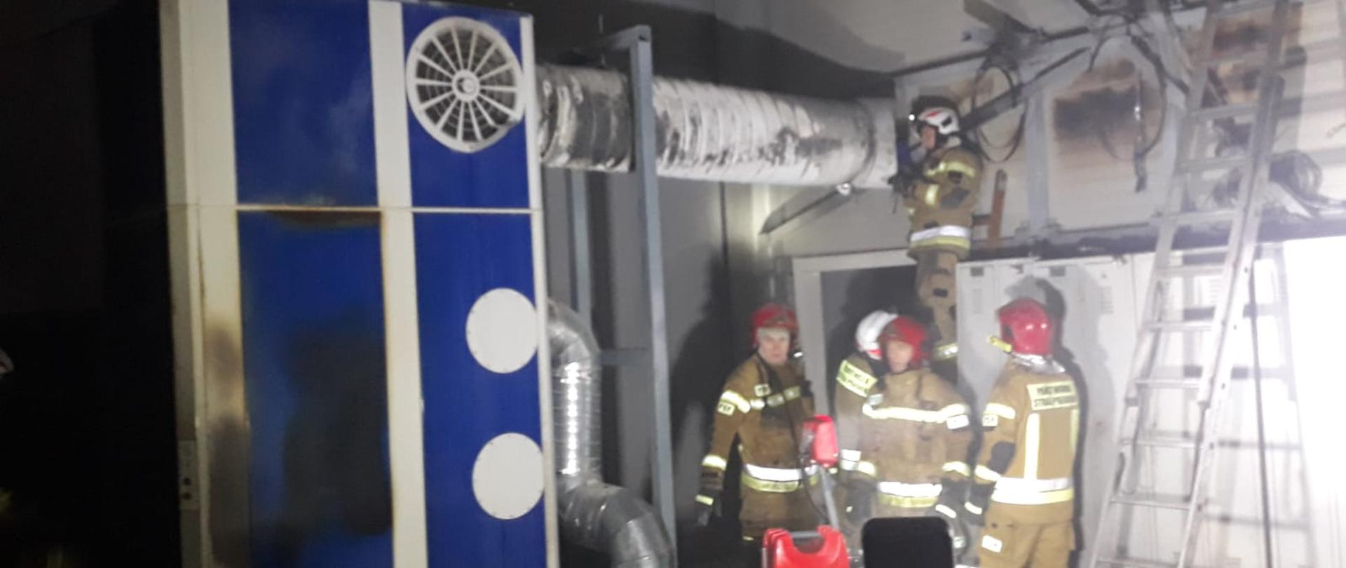 POŻAR NA HALI PRODUKCYJNEJ. Na zdjęciu widać maszynę, która uległa zapaleniu, strażaków podczas działań