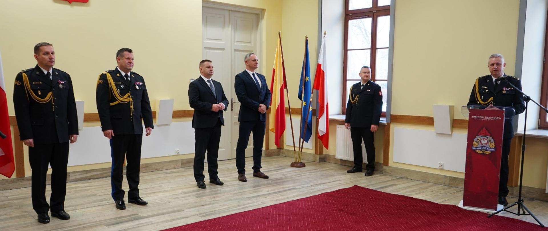 Strażacy i zaproszeni gości, w sali sztandarowej w trakcie uroczystej zbiórki z okazji zdania i przyjęcia pełnienia obowiązków Komendanta Miejskiego PSP.