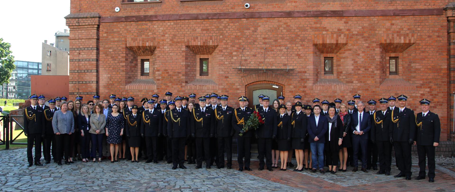 grupa ludzi stojacych przed murami obiektu , zdjecie grupowe