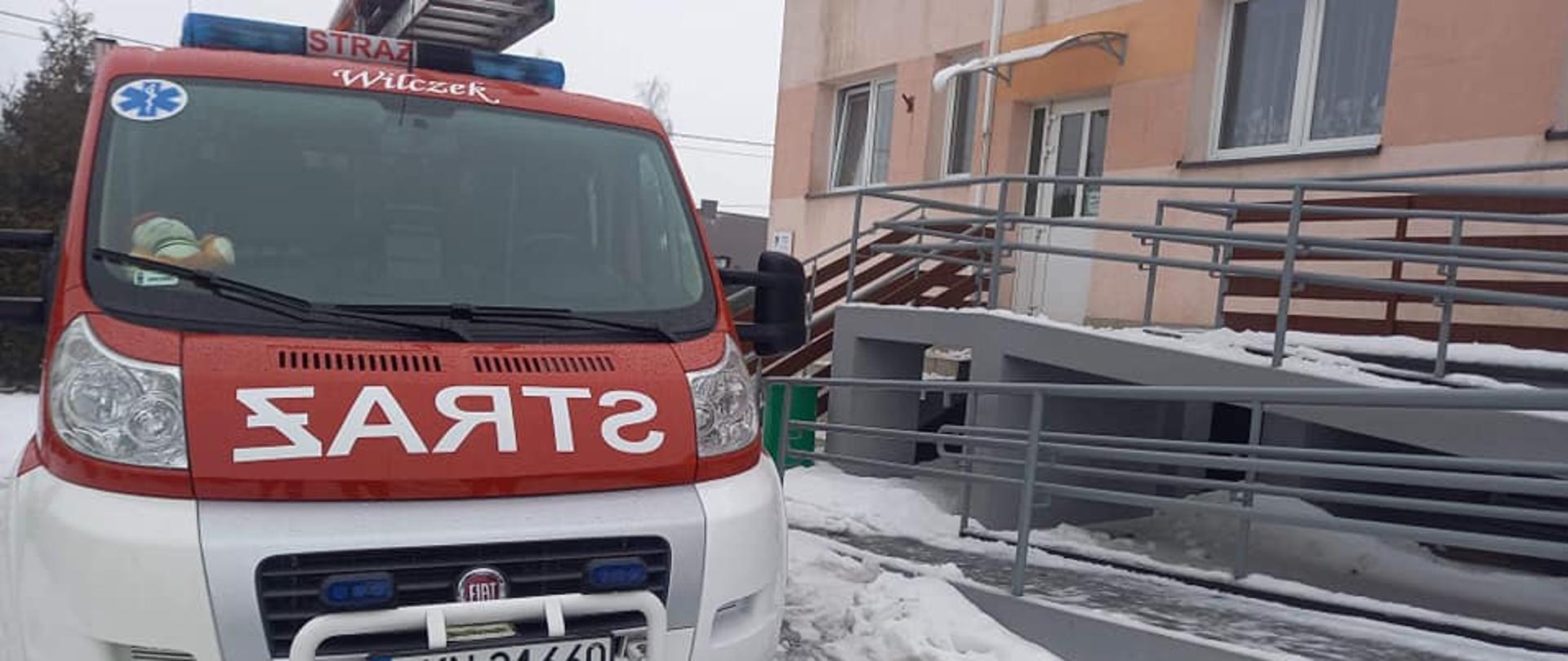 Zdjęcie przedstawia samochód straży pożarnej przed budynkiem przychodni 