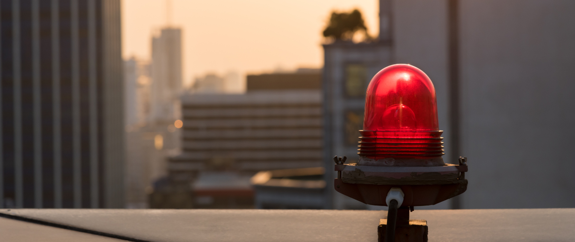 Zdjęcie czerwonej syreny alarmowej - w tle widok na drapaczu chmur w dużym mieście 