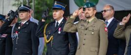 Zdjęcie przedstawia mężczyzn w strojach galowych OSP, PSP oraz Wojskowym salutujących podczas hymnu