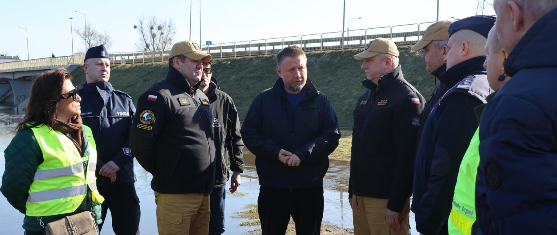 Grupa ludzi rozmawiających ze sobą na zewnątrz.