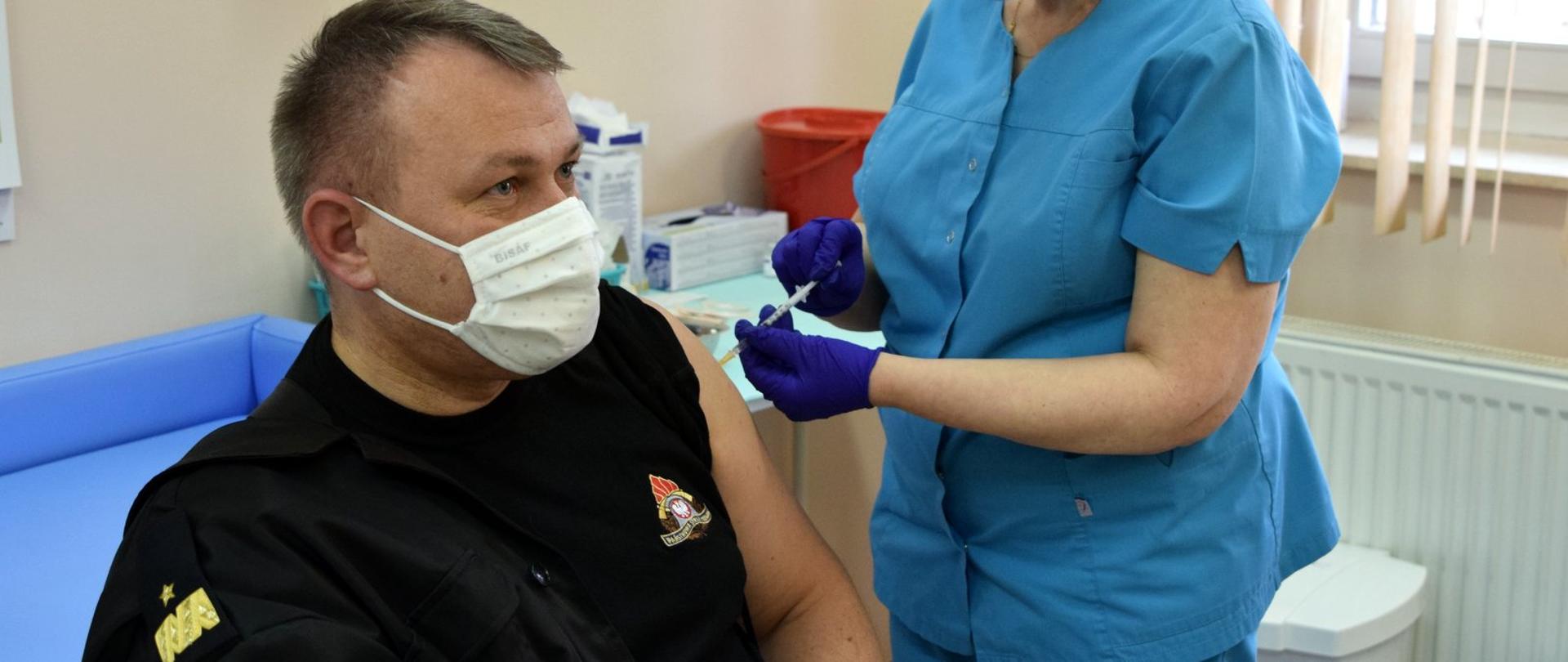 Na zdjęciu podkarpacki komendant wojewódzki Państwowej Straży Pożarnej jest szczepiony przeciw COVID-19