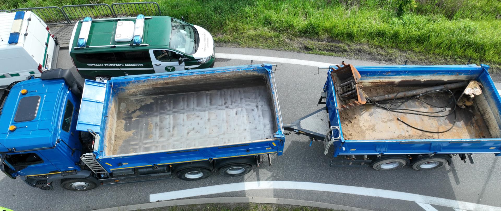 Widok z góry na niebieską ciężarówkę z dwoma przyczepami, obok samochód służbowy ITD.