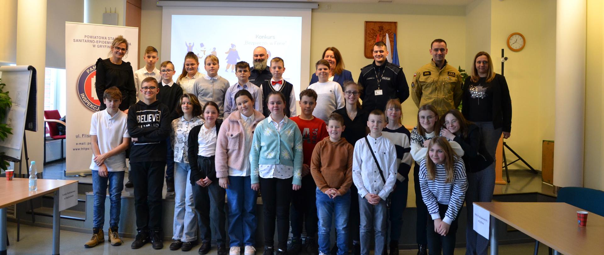 Pomieszczenie uczestnicy wraz z organizatorami wykonują zdjęcie grupowe. 