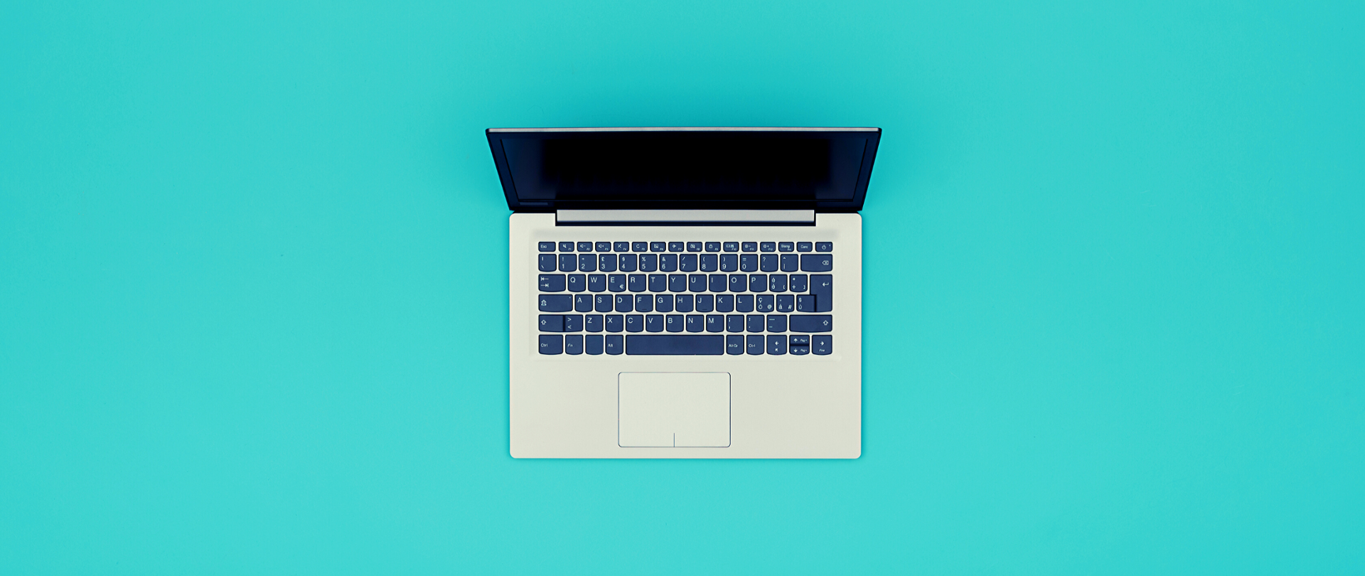 Otwarty laptop na turkusowym tle, widziany z góry