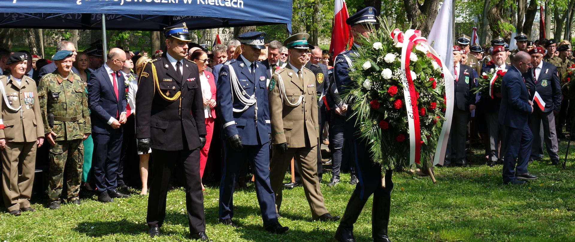 Zdjęcie przedstawia Świętokrzyskiego Komendanta Wojewódzkiego PSP razem z przedstawicielami służb mundurowych z wiązanką.