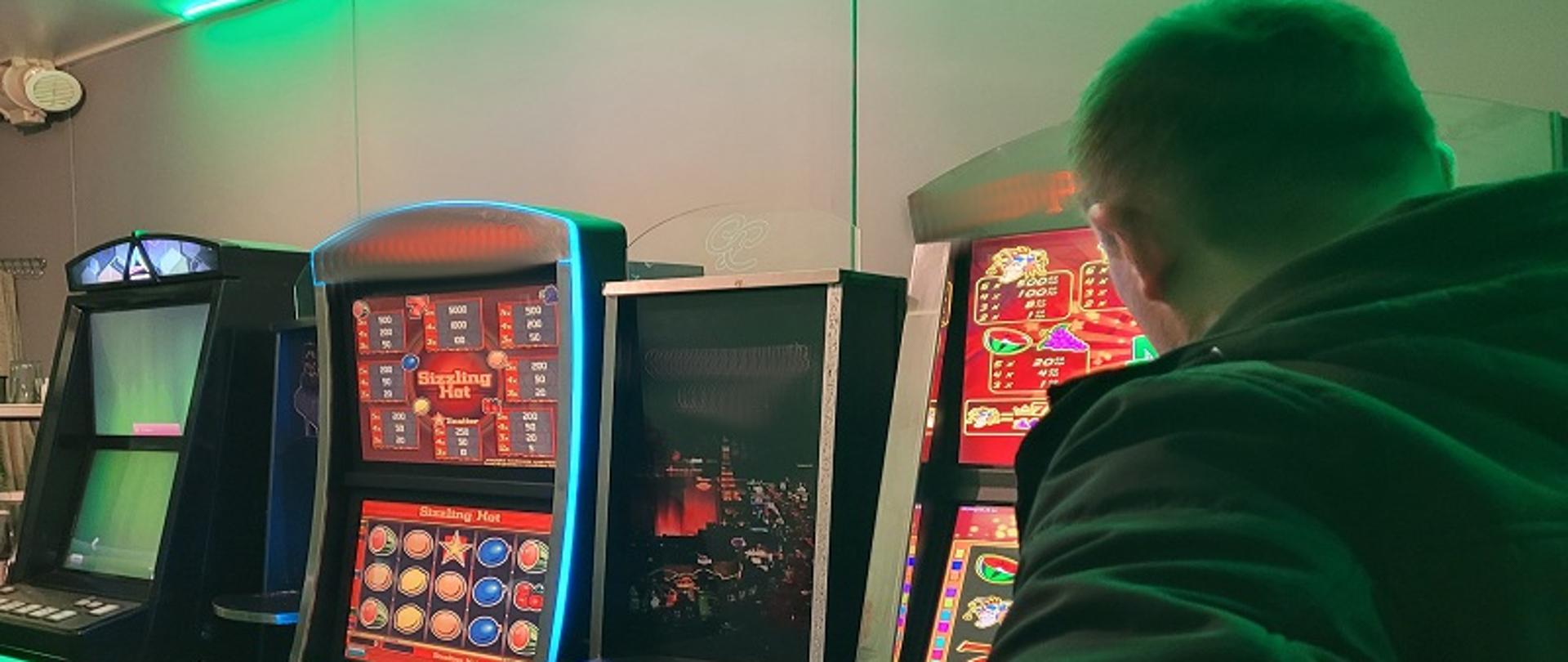 Funkcjonariusz stoi przed nielegalnymi automatami do gier hazardowych.