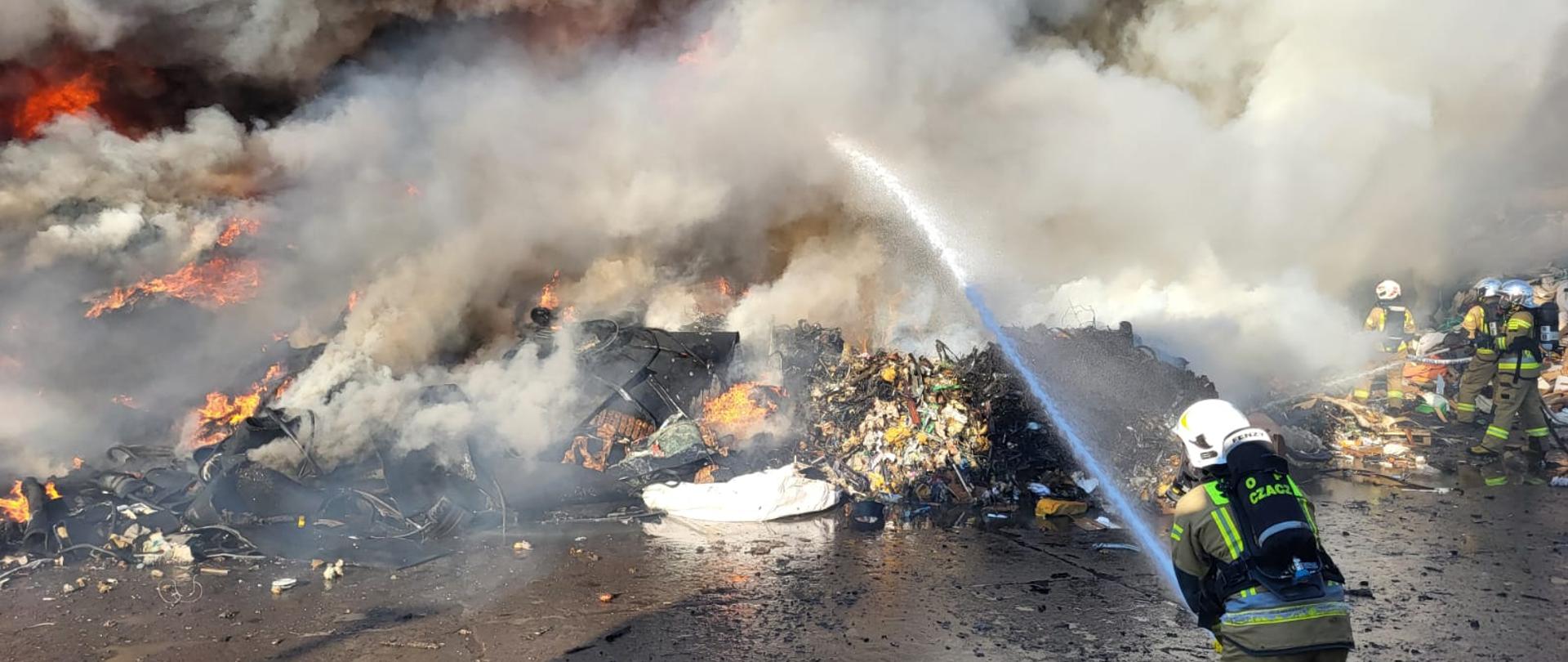 Strażacy prowadzą działania gaśnicze podczas pożaru odpadów, panuje duże zadymienie