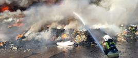 Strażacy prowadzą działania gaśnicze podczas pożaru odpadów, panuje duże zadymienie