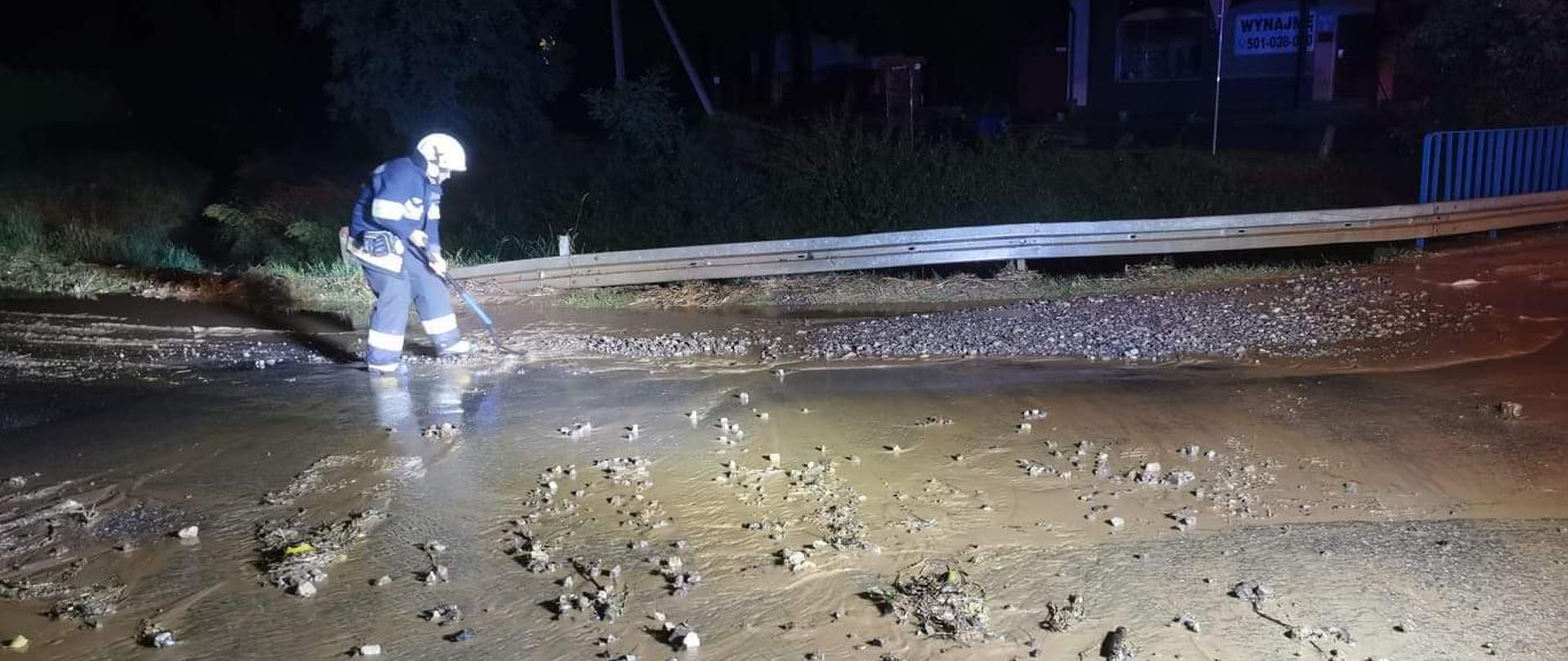 Usuwanie błota przez strażaków z jezdni