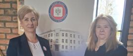 Na pierwszym planie widoczne są dwie pracownice oddziału, stojące przy banerze z napisem i logo Państwowej Inspekcji Sanitarnej.