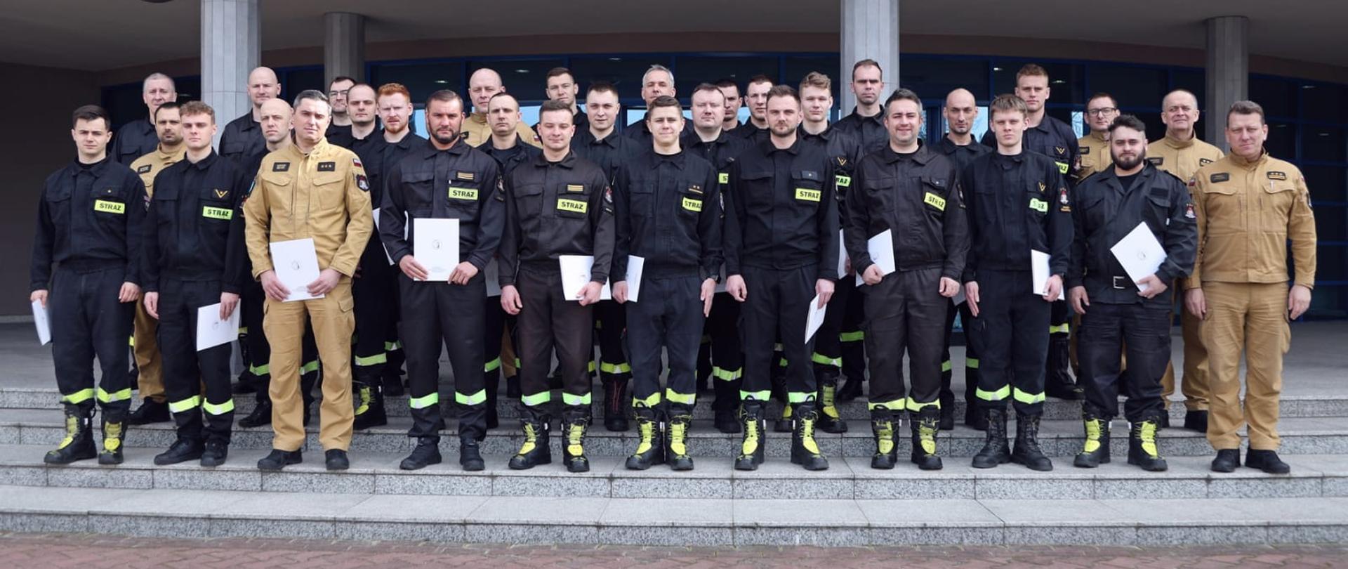 Pamiątkowe zdjęcie grupowe strażaków będących uczestnikami szkolenia z zakresu transportu towarów niebezpiecznych (30 osób) w towarzystwie trzech oficerów CS PSP