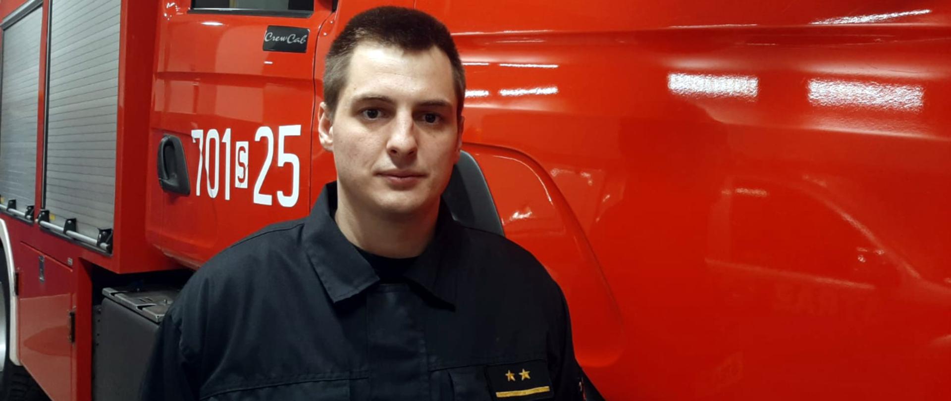 na zdjęciu na tle samochodu stoi strażak mł. kpt. Piotr Talik z Komendy Powiatowej PSP w Żywcu .