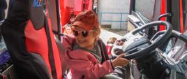 
Zdjęcie przedstawia dziecko siedzące za kierownicą pojazdu strażackiego.