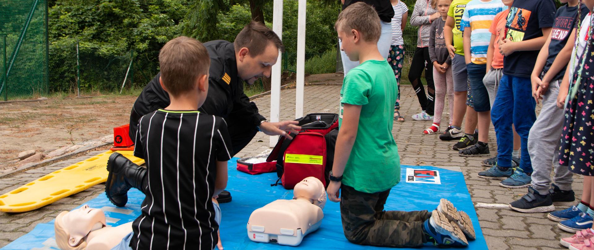 Na zdjęciu widać grupę dzieci podczas zajęć praktycznych z pierwszej pomocy 