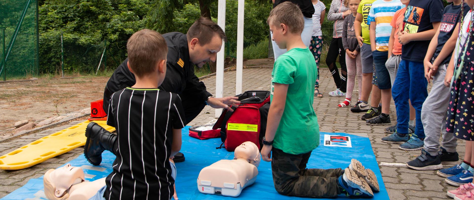 Na zdjęciu widać grupę dzieci podczas zajęć praktycznych z pierwszej pomocy 