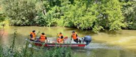 Strażacy , policjant i dwójka dzieci w łodzi ratowniczej na rzece Kamienna