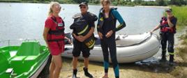 "Kręci mnie bezpieczeństwo nad wodą". Akwen w podrawickim Sierakowie. Na pierwszym planie trzech strażaków, członków OSP w Rawiczu oraz ratowniczka WOPR. Stoją oni na plaży na tle pontonu i roweru wodnego. W głębi widoczny akwen i las. 