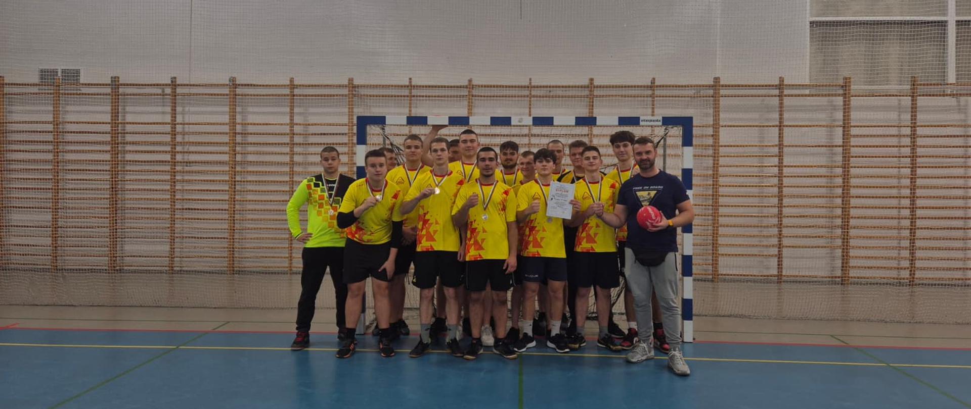 Drużyna stojąca w bramce w żółtych koszulach prezentujecie medale
