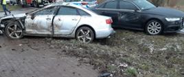 Na zdjęciu widać dwa rozbite samochody osobowe marki Audi stojące na poboczu drogi.