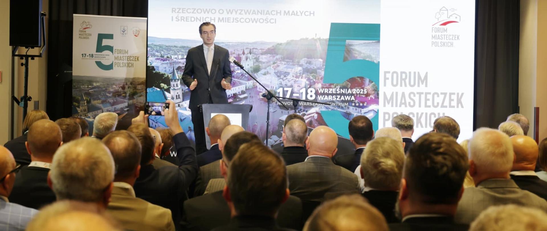 Wiceminister Jan Szyszko na scenie w mównicy z mikrofonem stoi i mówi do publiczności