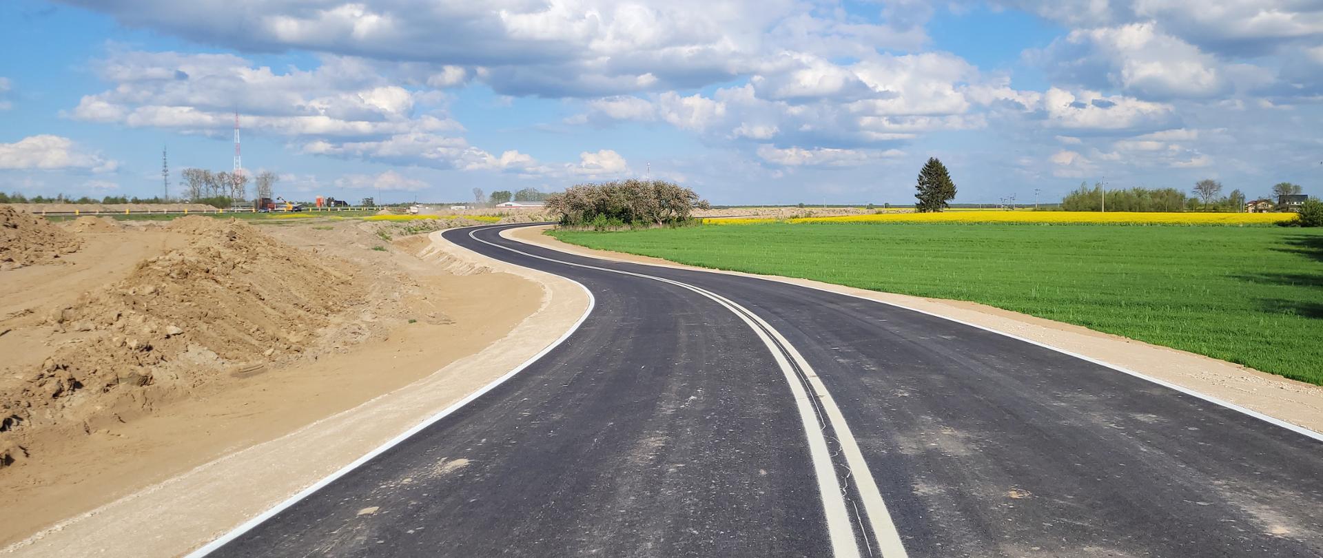 Wijąca się obok łąki droga asfaltowa 