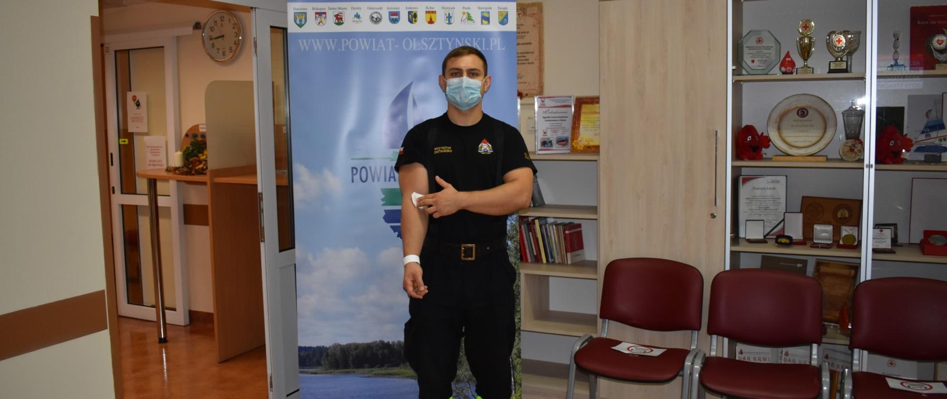 Zdjęcie przedstawia funkcjonariusza z Komendy Miejskiej PSP w Olsztynie po oddaniu krwi w ramach akcji krwiodastwa
