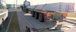 Ciężarówka przewożąca dwa betonowe słupy stoi tuż za przenośnymi wagami wielkopolskiej ITD.