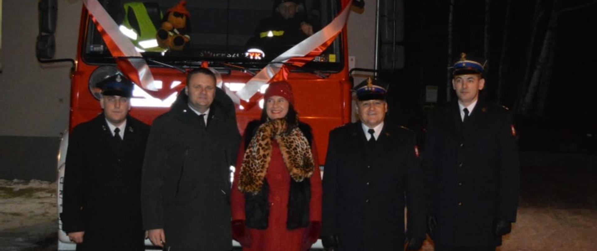 Zaproszeni goście na tle samochodu pożarniczego.