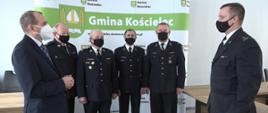 Zdjęcie przedstawia wójta gminy Kościelec, komendanta powiatowego PSP w Kole oraz druhów z gminy Kościelec podczas wręczenia decyzji o włączeniu jednostki OSP Trzęśniew do Krajowego Systemu Ratowniczo-Gaśniczego