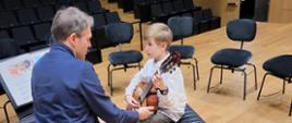 Uczeń grający na gitarze z prowadzącym warsztaty na scenie sali koncertowej PSM