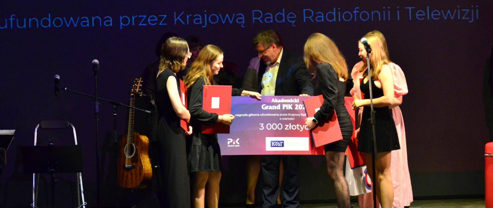 Zdjęcie w poziomie. Przewodniczący KRRiT w otoczeniu laureatek konkursu