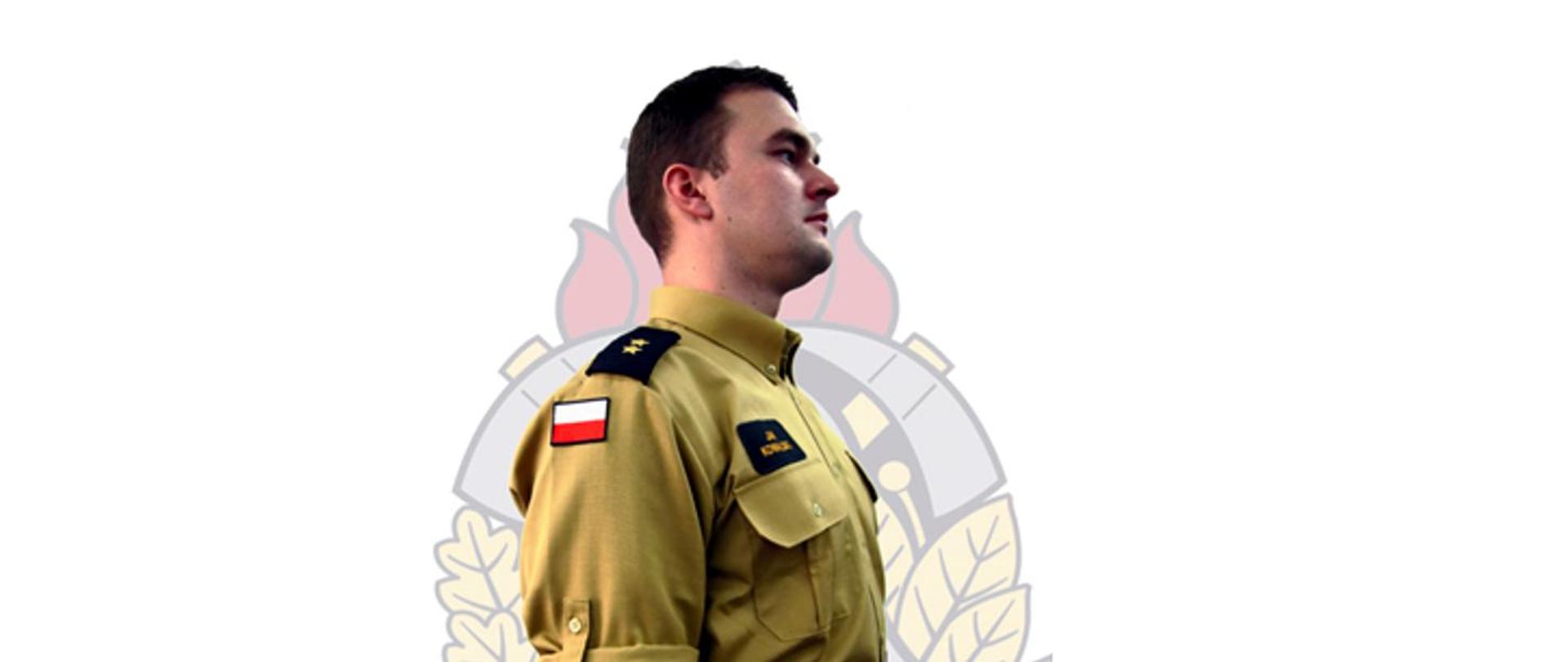 Nowe umundurowanie w Państwowej Straży Pożarnej - strażak prezentujący prawy profil ubrany w koszulę i spodnie służbowe. W tle znak wodny logo Państwowej Straży Pożarnej,