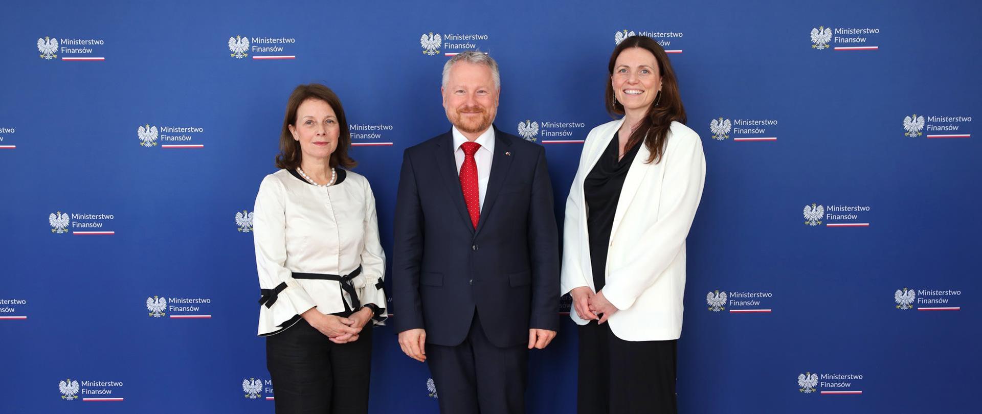 Wiceminister Jurand Drop, Wicedyrektor Dyrekcji Zarządzania Publicznego OECD Gillian Dorner oraz Nathalie Berger dyrektor ds. wsparcia reform państw członkowskich w strukturach Komisji Europejskiej, w tle ścianka z napisem Ministerstwa Finansów