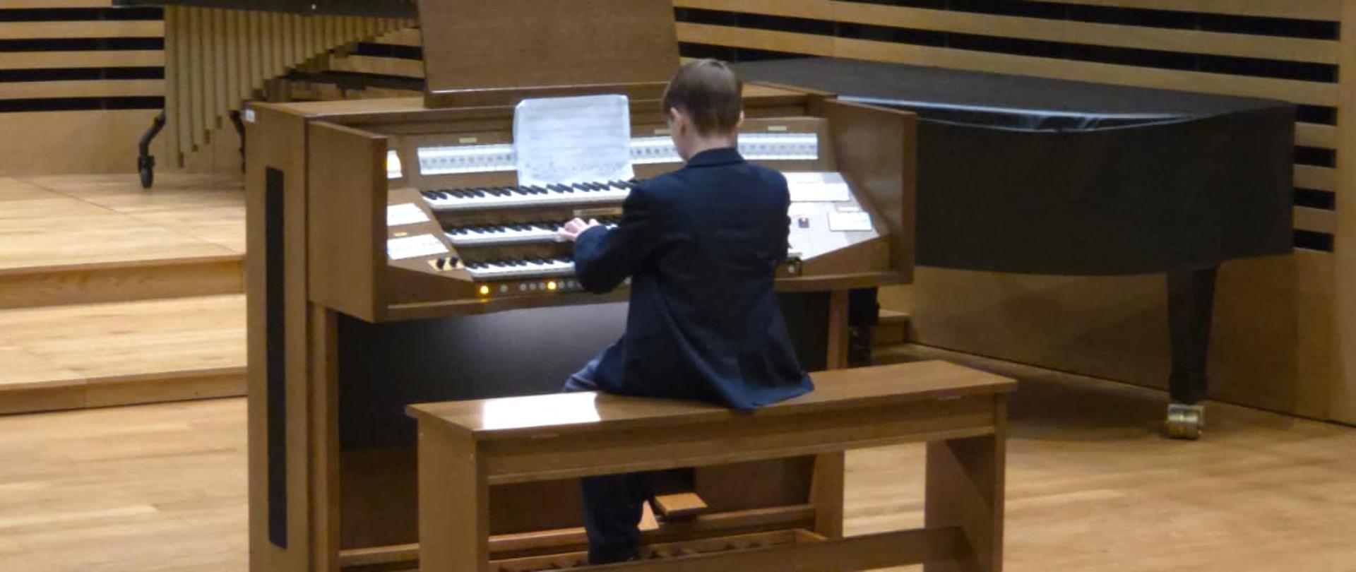 Chłopiec gra na organach.