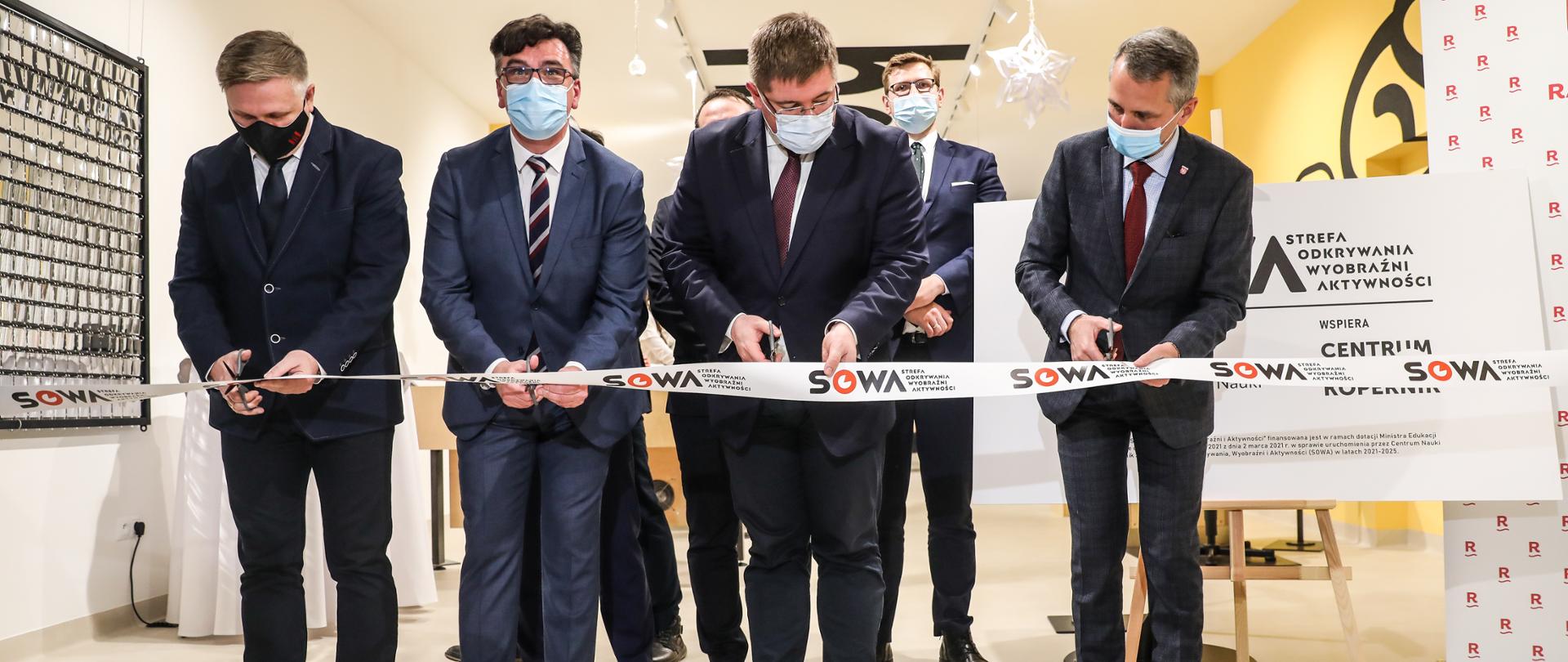 Otwarcie SOWA w Raciborzu z udziałem wiceministra Tomasza Rzymkowskiego, wiceminister Tomasz Rzymkowski wraz z innymi uczestnikami uroczystości, przecina symboliczna wstęgę.
