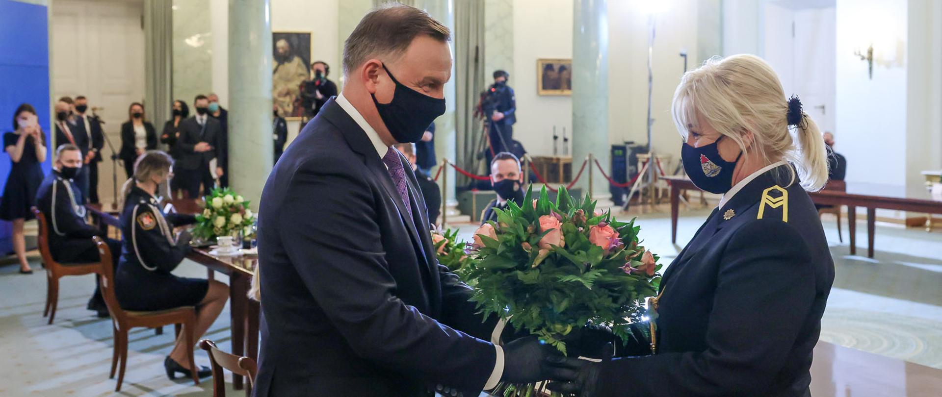 Prezydent wręcza bukiet kwiatów kobiecie strażak PSP