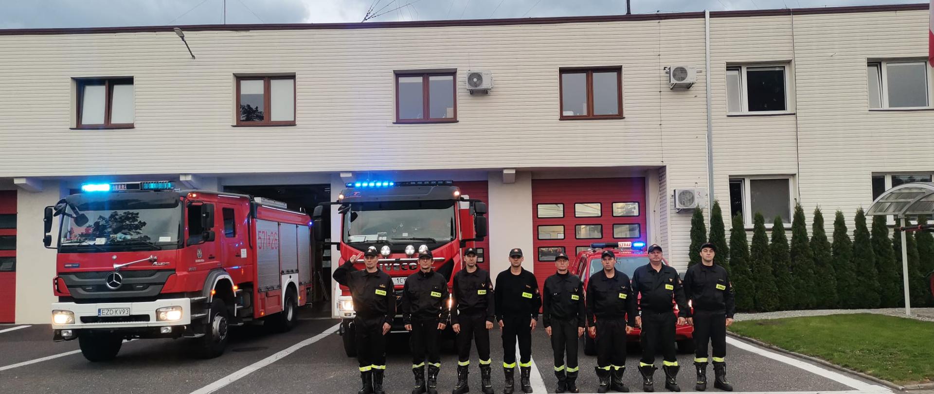 Zdjęcie ukazuje zbiórkę zduńskowolskich strażaków (zmiana służbowa III) przed budynkiem garażu. W tle widać samochody ratowniczo-gaśnicze z włączona sygnalizacją świetlną i akustyczną. Dowódca zmiany salutuje oddając hołd_śp._asp._sztab._Janowi_Biernatowi.
