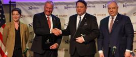 Prezes KGHM Polska Miedż Marcin Chludziński i dyrektor generalny NuScale Power John Hopkin podają sobie dłonie po podpisaniu umowy o współpracy między obiema firmami, po prawej stronie od prezesa KGHM stoi wicepremier i minister aktywów państwowych Jacek Sasin
