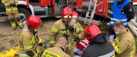 Strażacy udzielają kwalifikowanej pierwszej pomocy osobie poszkodowanej.