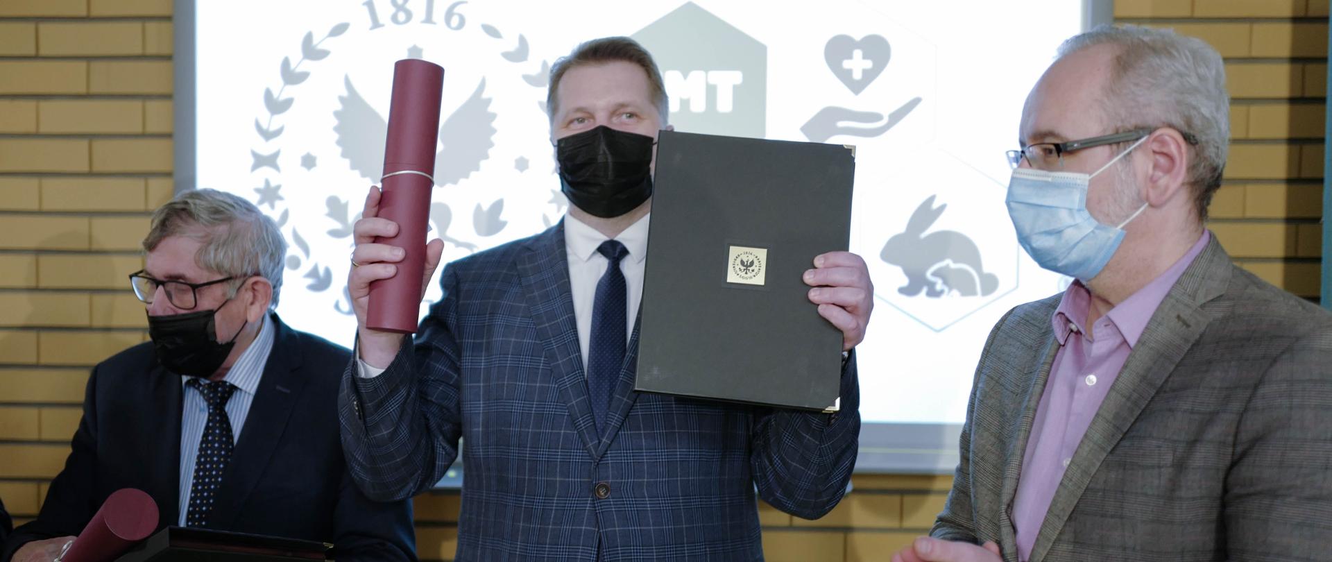 Otwarcie Centrum Medycyny Translacyjnej SGGW w Warszawie z udziałem ministra Przemysława Czarnka, minister Przemysław Czarnek pokazuje pamiątkowe dokumenty.